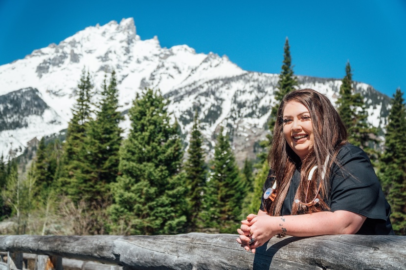 A smiling traveling nurse taking a photo in front of a snowy mountain.
