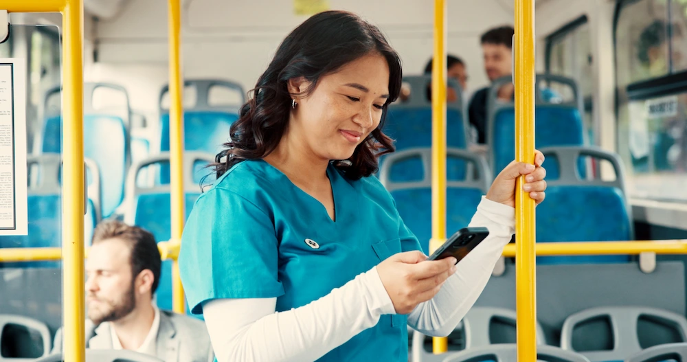 Travel technologist checking their phone while riding to work on a bus.