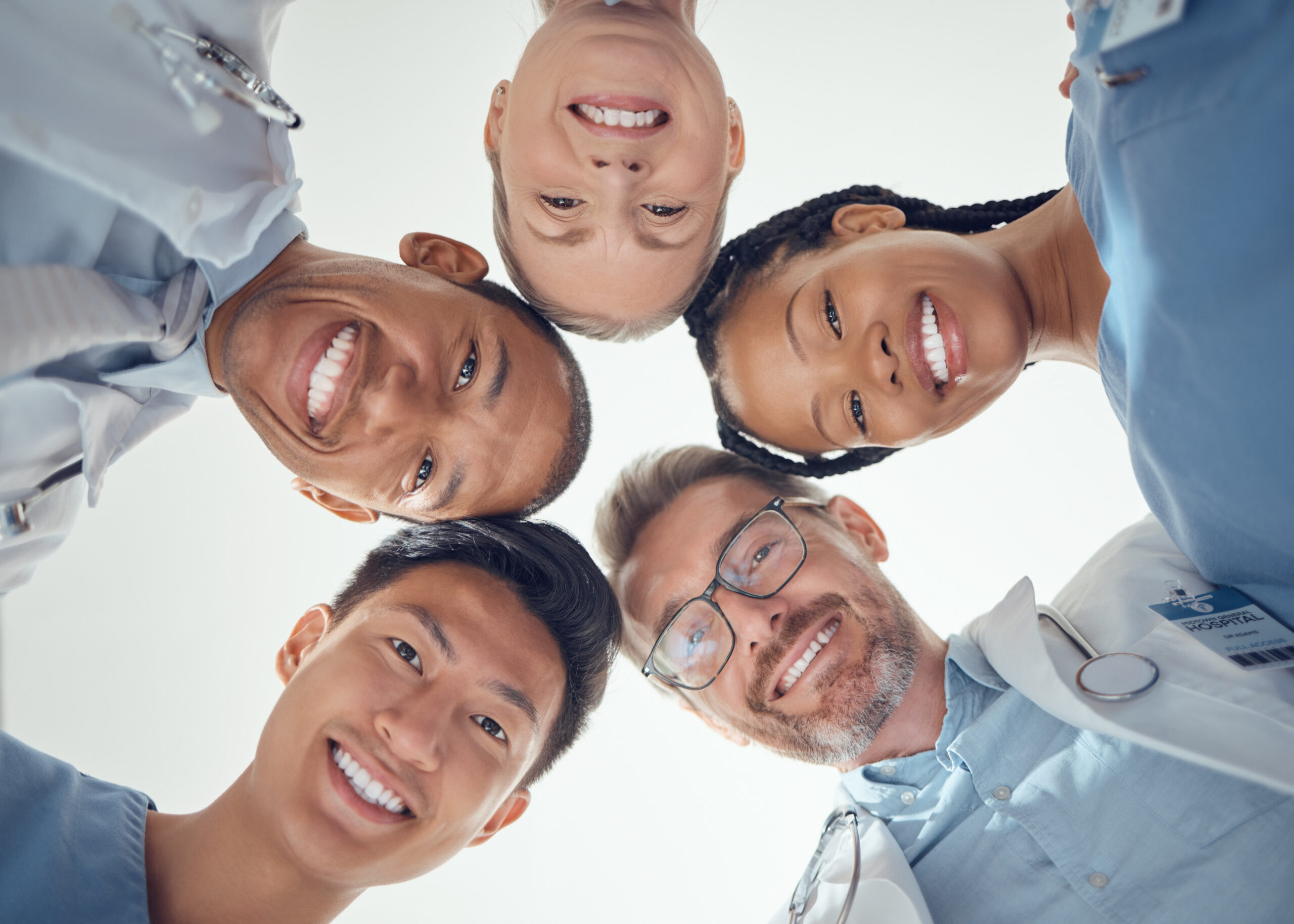 Smiling medical team standing in a circle and looking down at the camera.